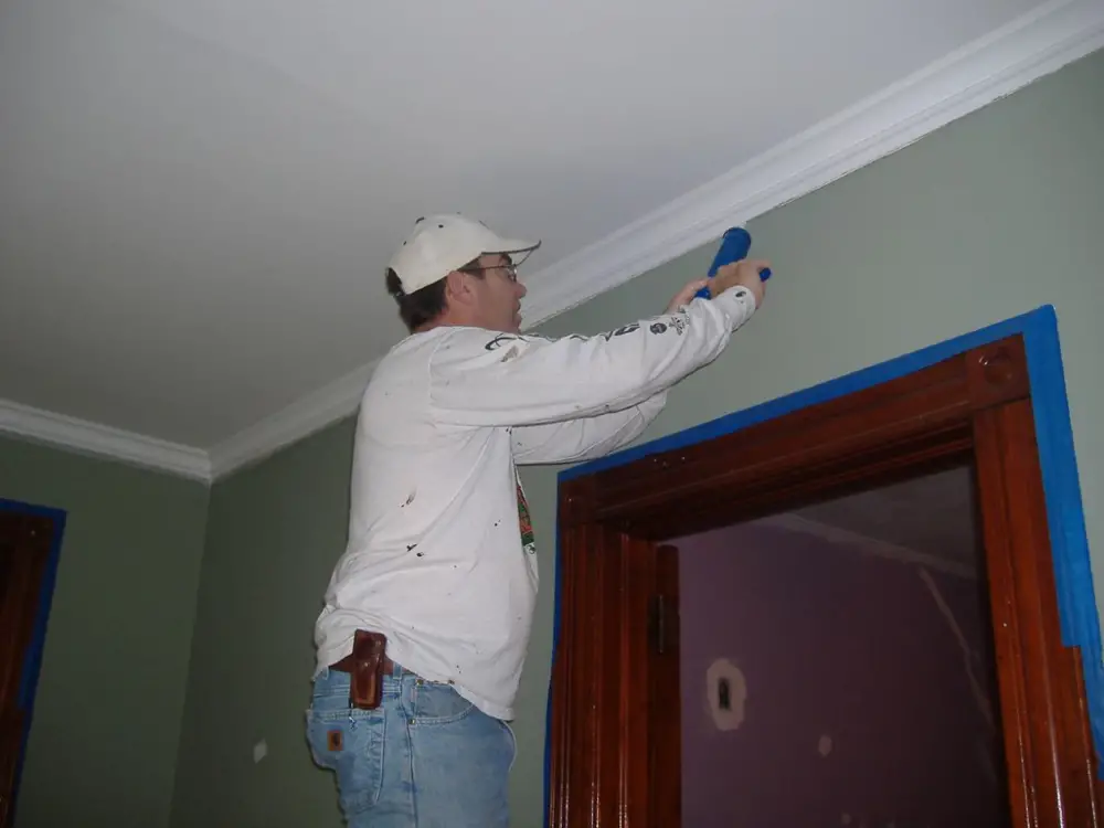 A contractor sealing home air leak by applying caulk.