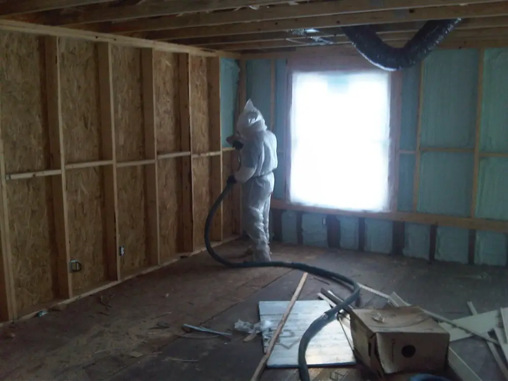An image of a worker sealing home air leak.